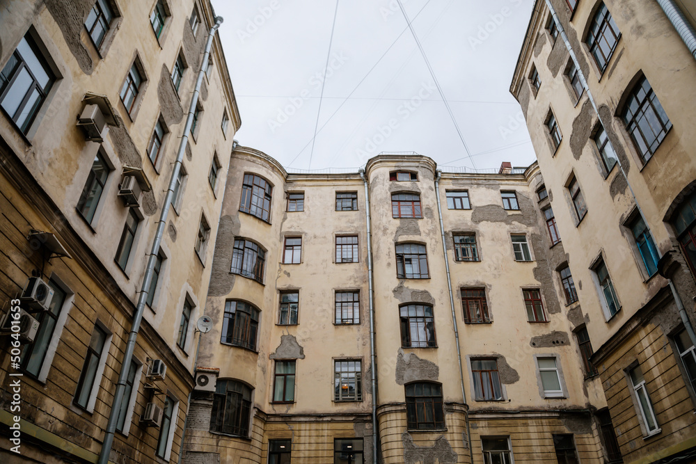 Saint Petersburg, Russia, 18 October 2021: Hight narrow courtyards called well in center, old architecture, Bottom up view, piece of sky is visible between profitable yellow houses, Dark inner
