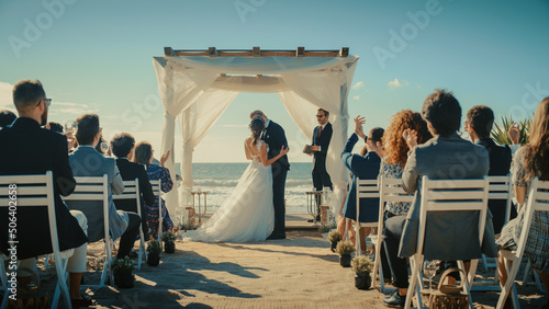 Beautiful Bride and Groom During an Outdoors Wedding Ceremony on a Beach Near the Ocean. Perfect Venue for Romantic Couple to Get Married, Kiss and for Friends with Multiethnic Cultures to Celebrate.