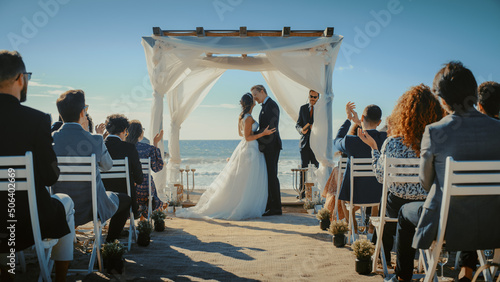 фотографія Beautiful Bride and Groom During an Outdoors Wedding Ceremony on a Beach Near the Ocean