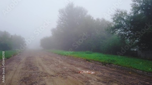 Walking on broken road in fog. Misty autumn landscape and damaged path at dusk. Motion on foggy street