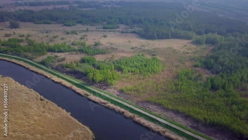 Aerial view of the lake overgrown with brown reeds and blue water, lake Liepaja, Latvia, sunny day, calm weather, high altitude wide angle drone shot moving forward, camera tilt down photo