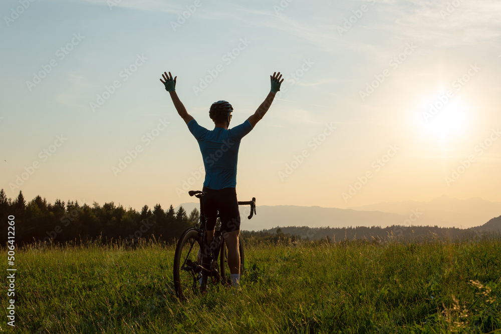 Male athlete professional racing cyclist riding a bike with arms raised above the head, in a victory pose Male athlete professional racing cyclist riding a bike with arms raised above the head, in a victory pose