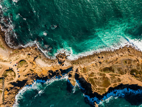 Azure clear water hits the rocky coast of coral beach. Aerial top view