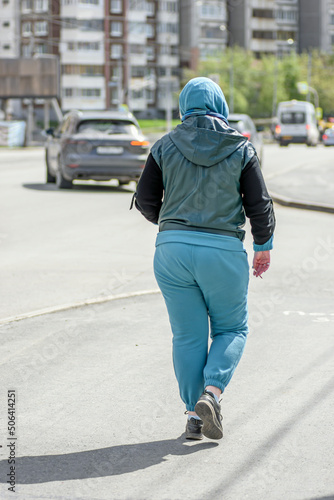 A woman in a tracksuit walks along the sidewalk on a spring day © vladimir subbotin