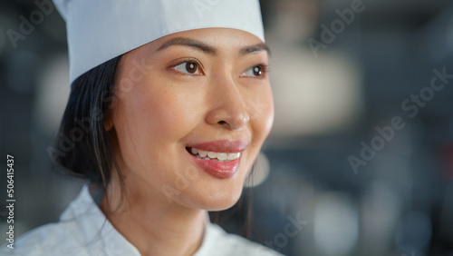 World Famous Restaurant: Portrait of Smiling Asian Female Chef Cooking Delicious, Steamy, Authentic Food, Happy With Her Finished Dish in a Kitchen. Preparing affordable Haute Cuisine gourmet