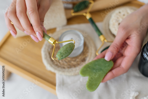 Green jade and gua sha in female hands. Facial massage