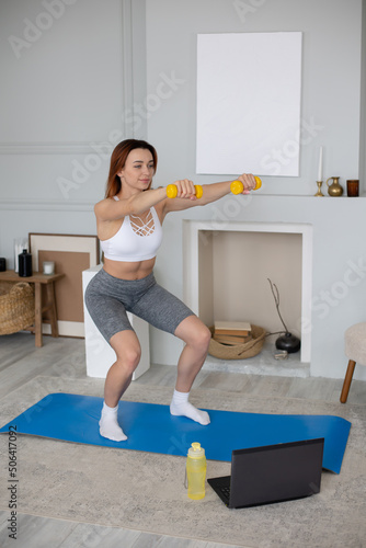 Young woman performs fitness exercises at home