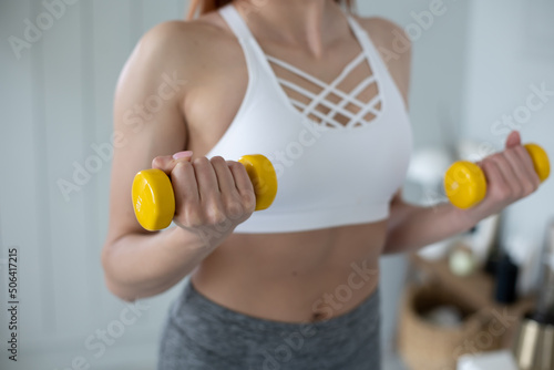 Yellow dumbbells in the hands. Athletic female body