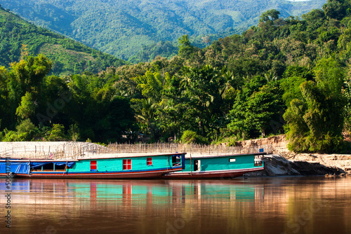 Traditional Laos ferry boats dock on the Mekong Riverbank.