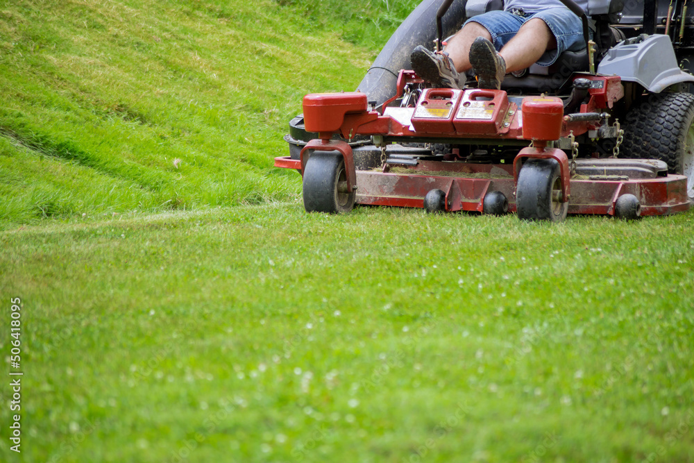 Obraz premium Man mows lawn using gasoline-powered self-propelled lawn mower on cutting grass with lawn mower.