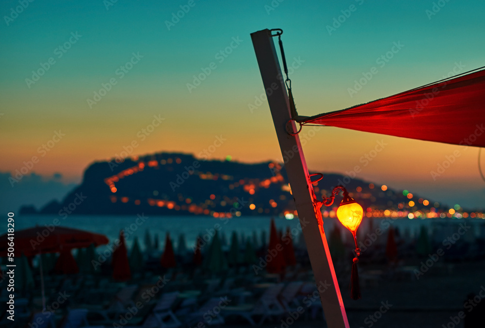 Lantern on the beach at sunset with Alanya peninsula on the background