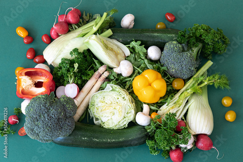 Close-up, different bright vegetables on a green background, flat lay.