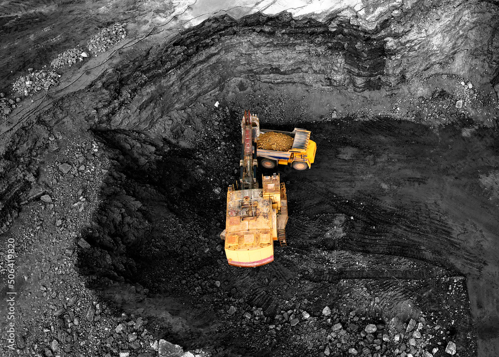 Coal mining in an open pit. Mining excavator loads coal in haul truck in  quarry. Excavator
