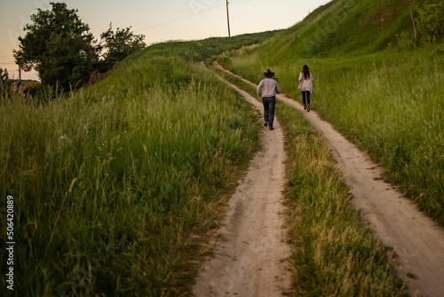 a man and a girl in rustic clothes run along a village road