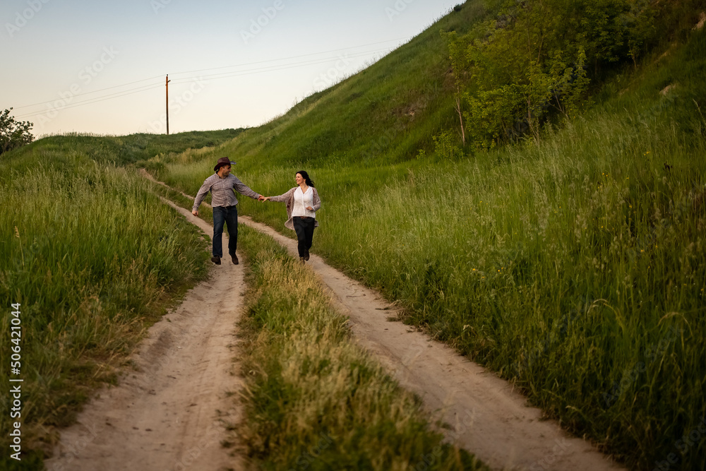 a man and a girl in rustic clothes run along a village road