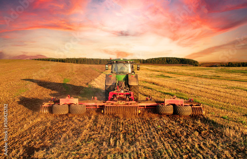 Obraz na plátně Tractor Plowing field on sunset