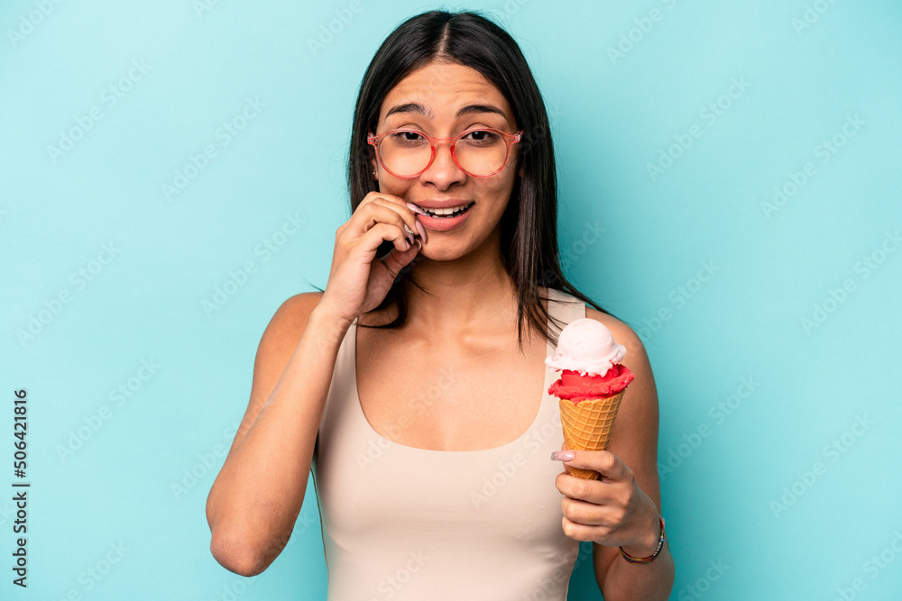 Young hispanic woman holding an ice cream isolated on blue background biting fingernails, nervous and very anxious. Young hispanic woman holding an ice cream isolated on blue background biting fingernails, nervous and very anxious.