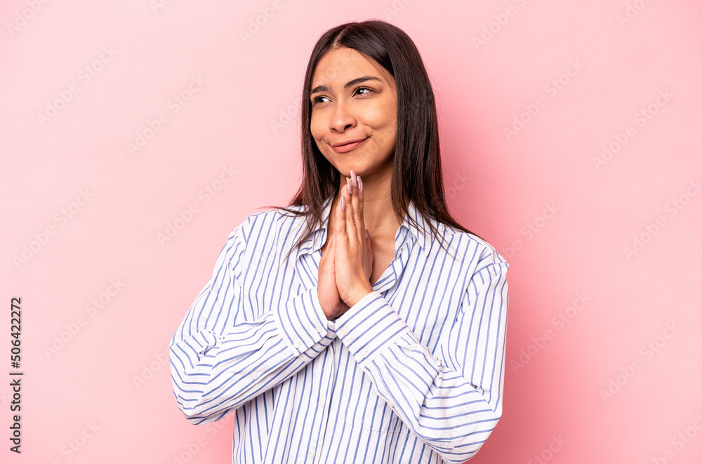 Young hispanic woman isolated on pink background praying, showing devotion, religious person looking for divine inspiration. Young hispanic woman isolated on pink background praying, showing devotion, religious person looking for divine inspiration.
