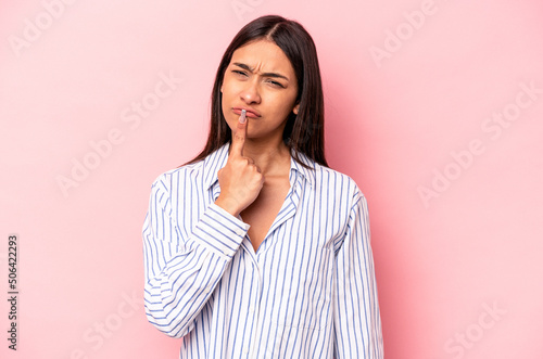 Young hispanic woman isolated on pink background thinking and looking up, being reflective, contemplating, having a fantasy.