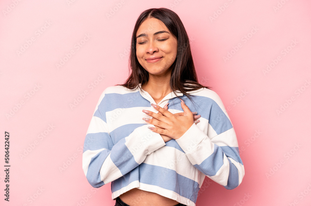 Young hispanic woman isolated on pink background has friendly expression, pressing palm to chest. Love concept. Young hispanic woman isolated on pink background has friendly expression, pressing palm to chest. Love concept.