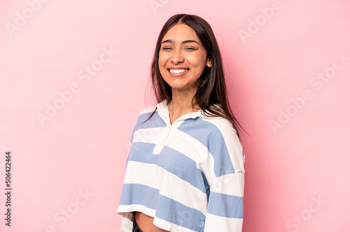 Young hispanic woman isolated on pink background confident keeping hands on hips. © Asier