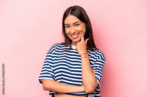 Young hispanic woman isolated on pink background smiling happy and confident  touching chin with hand.