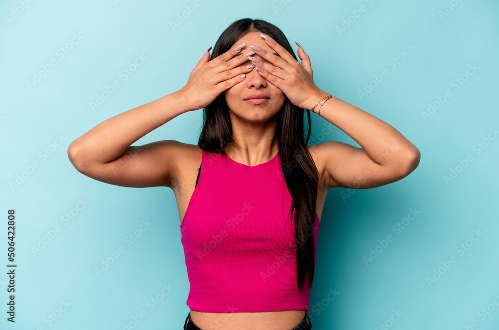 Young hispanic woman isolated on blue background afraid covering eyes with hands. Young hispanic woman isolated on blue background afraid covering eyes with hands.