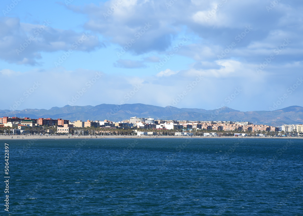 Fototapeta premium seascape of Mediterranean Sea. Coastline at Alboraya beach. View from sea to cityscape of Port Saplaya against the backdrop of the mountains. View blue seascape ocean. Coastal or coast view.