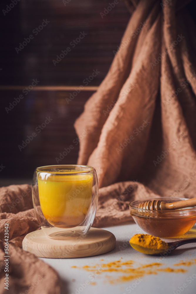 Turmeric latte, Cooking Golden Milk On Kitchen. Hot healthy drink. Milk, turmeric, honey