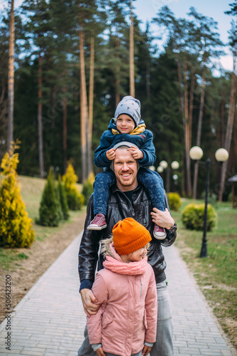 Father and two children walk in nature in autumn, spend time together, have fun.