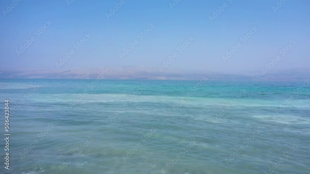 Drone shot flying over aqua colored crystal clear waters of the Dead Sea in Israel on a perfect sunny day. Sea floor with salt deposits can be clearly seen. Drone shot flying over aqua colored crystal clear waters of the Dead Sea in Israel on a perfect sunny day. Sea floor with salt deposits can be clearly seen.
