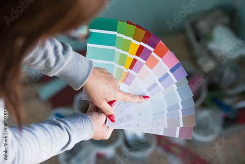 Close-up of a female designer choosing paint samples for walls. A girl looks at a color sample to create a project. Reconstruction of the house, architecture and interior design concept.