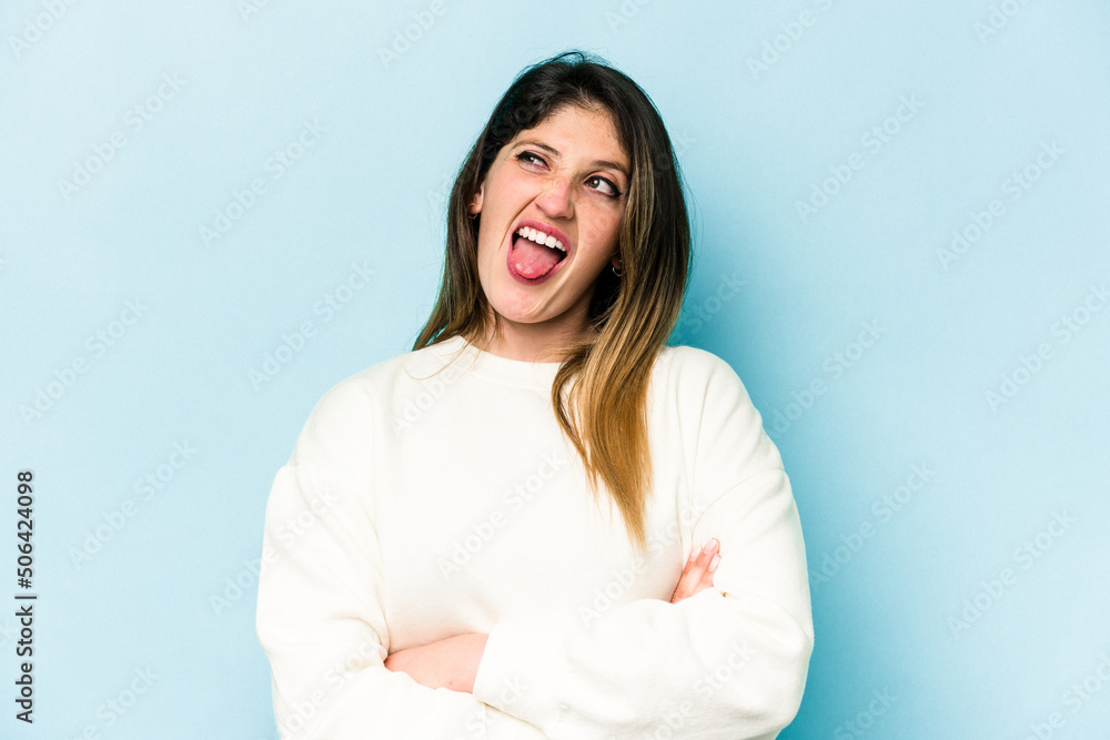 Young caucasian woman isolated on blue background funny and friendly sticking out tongue. Young caucasian woman isolated on blue background funny and friendly sticking out tongue.