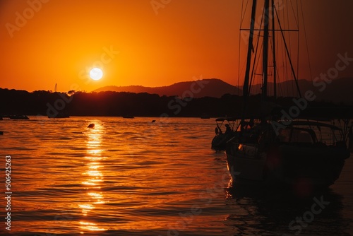 Obraz na plátně A white sailboat sails on the sea with an orange sunset