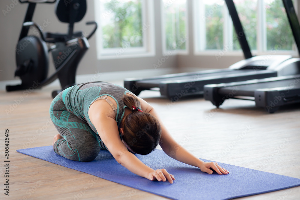 Young asian woman doing yoga with stretch muscles back in the fitness gym, female training practicing workout with yoga for bodycare in the home, rehab with flexible of body, sport concept. Young asian woman doing yoga with stretch muscles back in the fitness gym, female training practicing workout with yoga for bodycare in the home, rehab with flexible of body, sport concept.