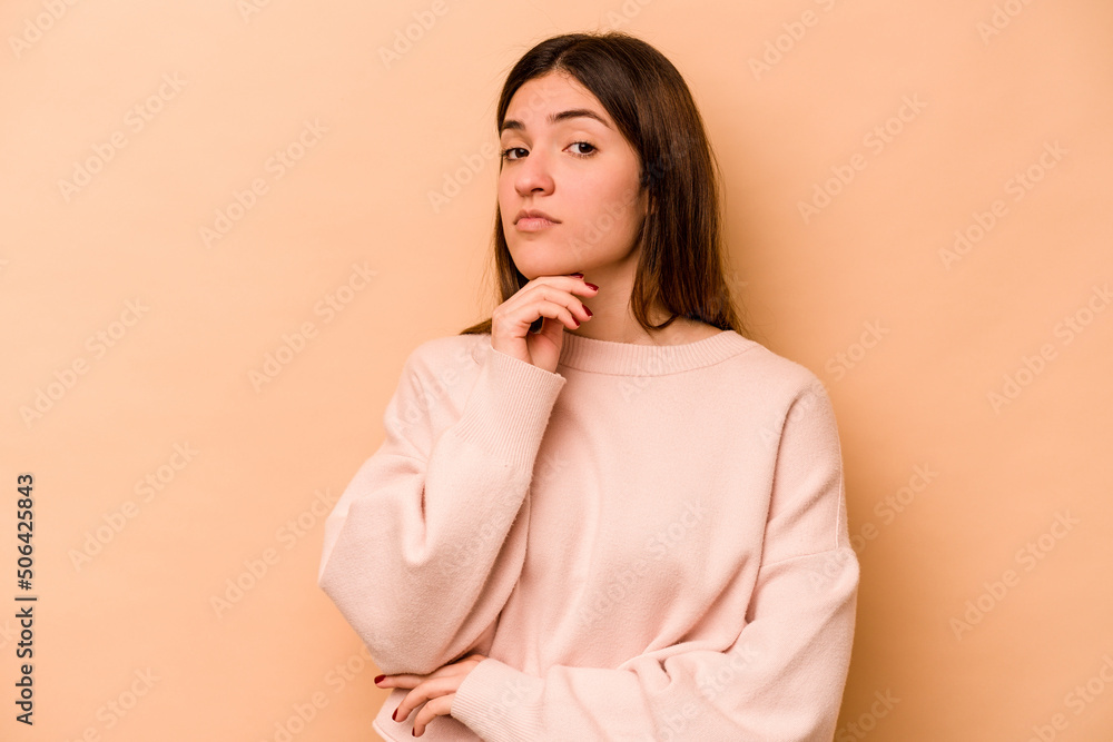 Young hispanic woman isolated on beige background suspicious, uncertain, examining you. Young hispanic woman isolated on beige background suspicious, uncertain, examining you.