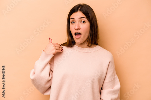 Young hispanic woman isolated on beige background laughing about something  covering mouth with hands.