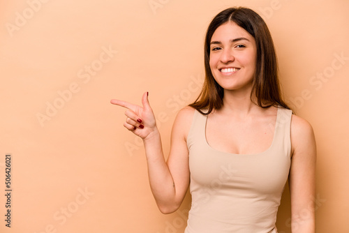 Young hispanic woman isolated on beige background smiling cheerfully pointing with forefinger away.