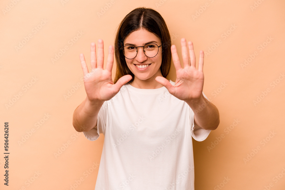 Young hispanic woman isolated on beige background showing number ten with hands. Young hispanic woman isolated on beige background showing number ten with hands.