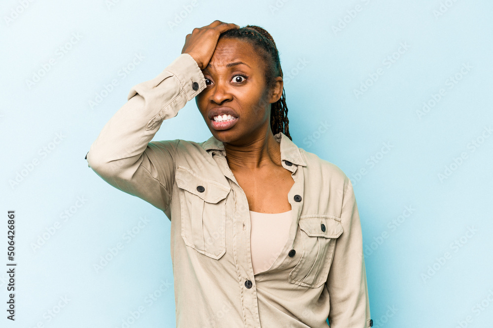 Young african american woman isolated on blue background forgetting something, slapping forehead with palm and closing eyes. Young african american woman isolated on blue background forgetting something, slapping forehead with palm and closing eyes.