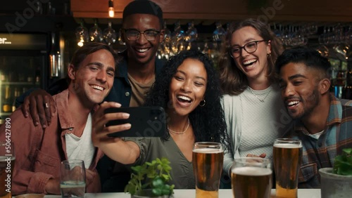 Diverse group of friends taking selfies in restaurant
