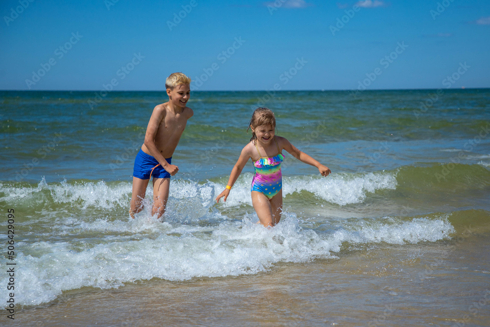 Brother and sister of having fun in water on beach and splashing Brother and sister of having fun in water on beach and splashing