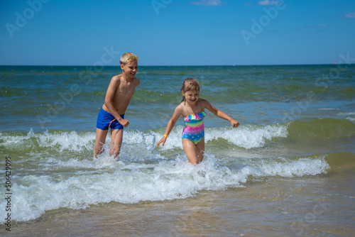 Brother and sister of having fun in water on beach and splashing