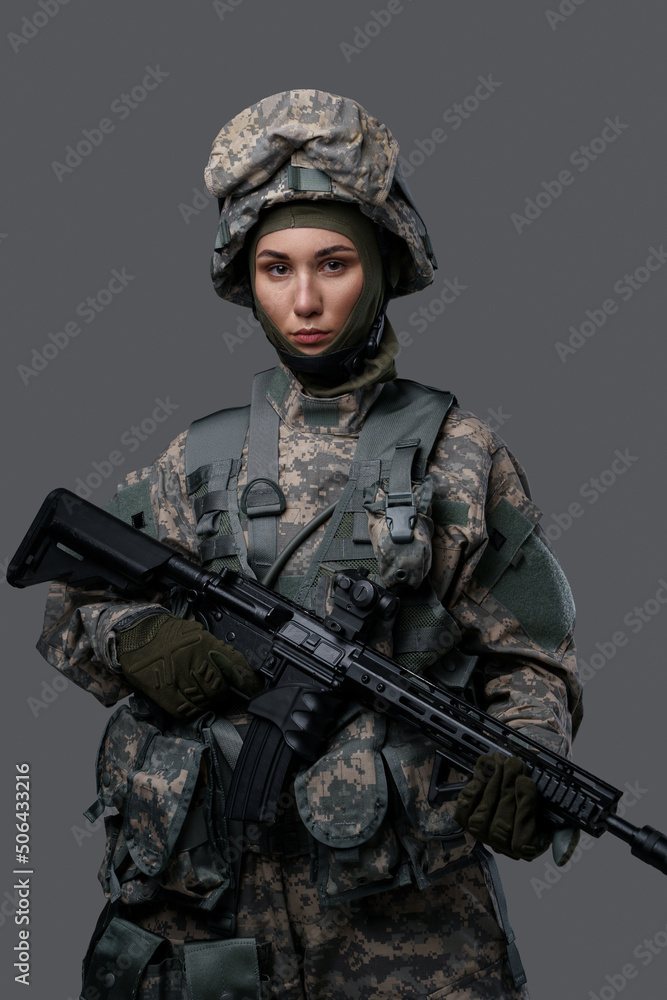 Studio shot of isolated on gray background woman soldier holding rifle. Studio shot of isolated on gray background woman soldier holding rifle.