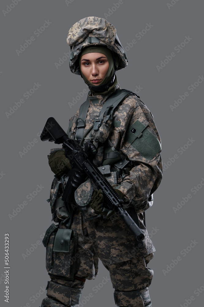 Studio shot of isolated on gray background woman soldier holding rifle. Studio shot of isolated on gray background woman soldier holding rifle.
