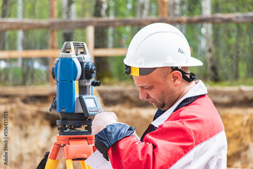 Construction of a residential area. Geodetic stakeout. Surveyor at a large construction site. A man with a tachometer during work. Makshader. photo