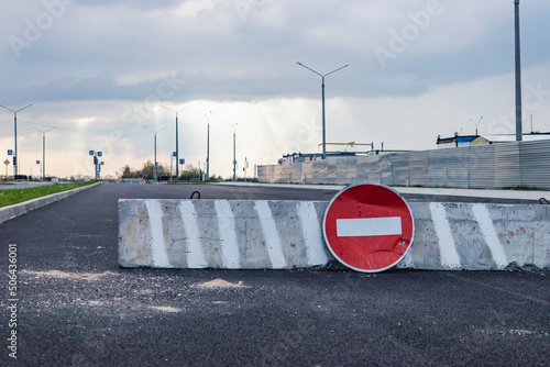 A stop road sign and concrete blocks block the entrance to the construction site. Closed road. Construction and road works.