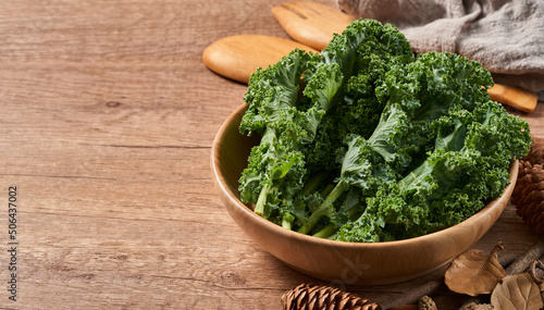 concept of fresh kale leaves salad in a bowl on wooden table background. green kale leaves salad food in the kitchen. spoon, fork                           