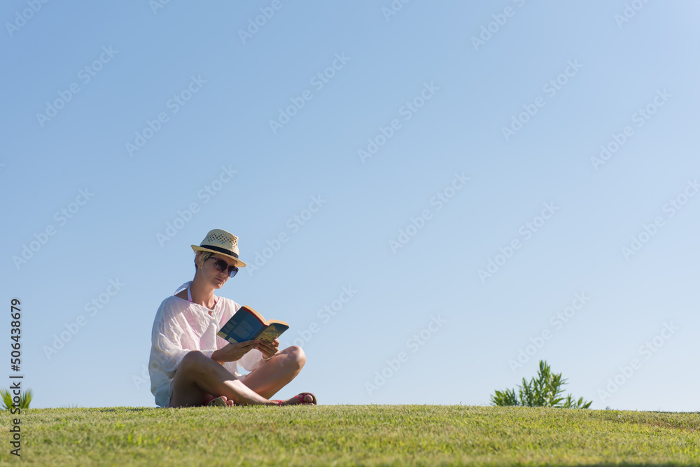 Woman lying and reading her favorite book on a meadow covered with fresh green grass on a sunny summer or spring day. Woman lying and reading her favorite book on a meadow covered with fresh green grass on a sunny summer or spring day.