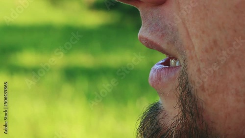 Portrait of young smoking iqos man closeup outdoor. Close up video of adult smoker in summer park
